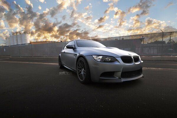 A sporty grey car on the sidewalk