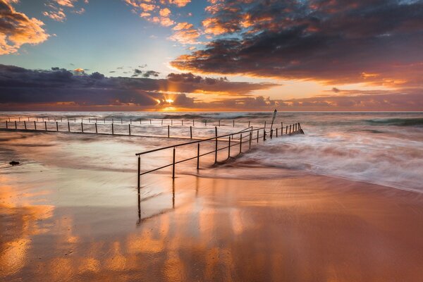 Vagues de la mer se brisent sur la balustrade creusée sur la plage