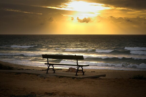 A bench by the sea at sunset