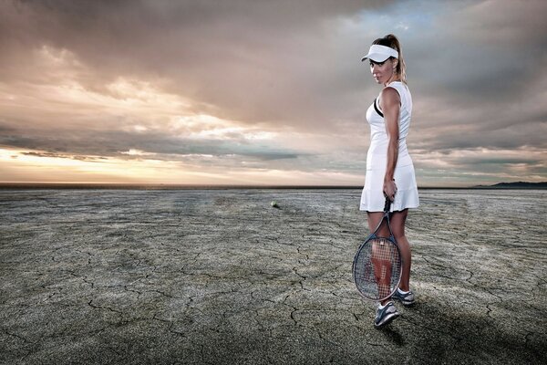 A lonely tennis player stands in the middle of the desert