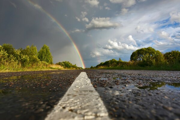 A road turning into a rainbow and a cloudy sky