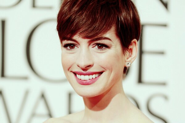 An actress with a short haircut and a snow-white smile