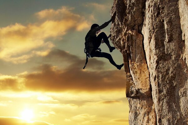 Scalatore che si arrampica sul Tramonto della montagna