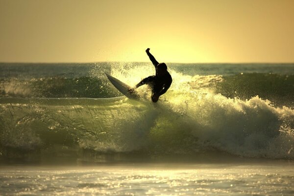 Surfista no mar agitado ao pôr do sol