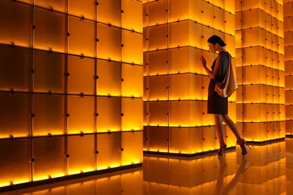 La niña está de pie junto a una pared arquitectónica iluminada