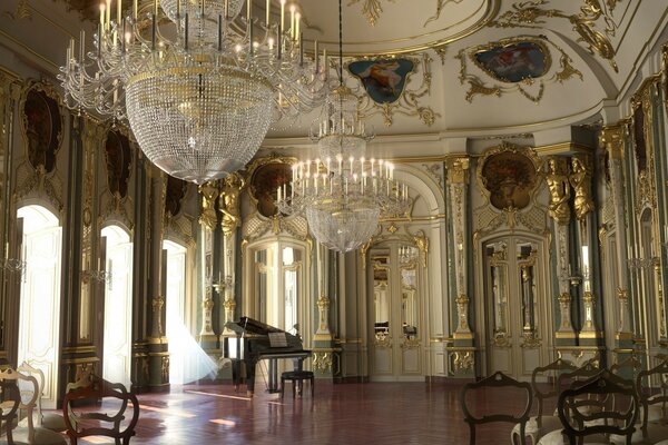 Sala de concertos no palácio com baixos-relevos, afrescos, dourado e grandes lustres de cristal