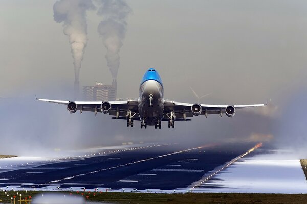 Fliegendes Flugzeug vor dem Hintergrund eines rauchigen Hauses