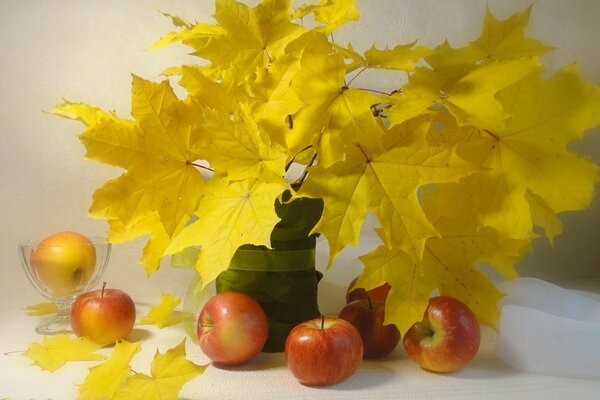 Hojas de otoño con manzanas en la mesa