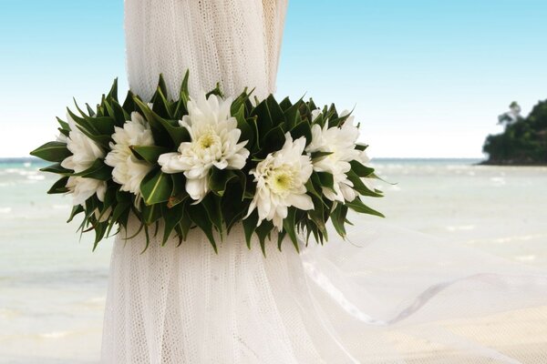 Soporte a uno entonces en tela blanca y decorado con flores blancas contra un mar de cielo azul