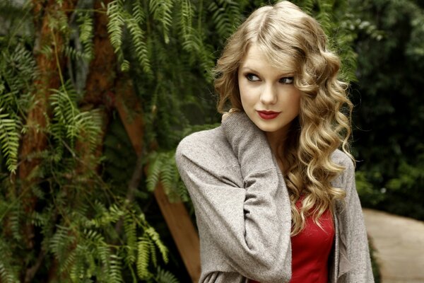 The blonde is sitting in the park under a tree