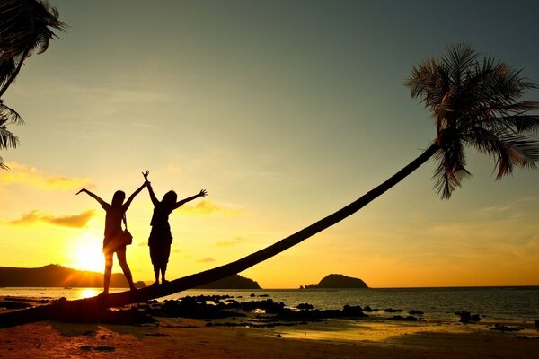 Due ragazze sulla spiaggia sullo sfondo del tramonto