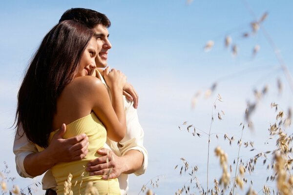 A couple in love walks through a field sown with cereals