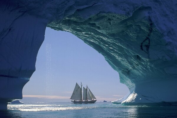 A sailboat under an iceberg. Mysteries of the ocean