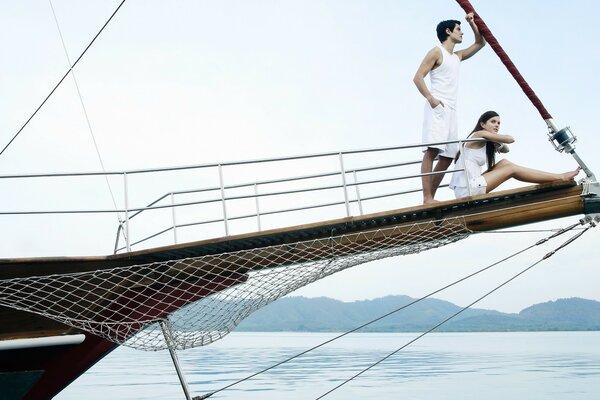 A girl with a young man on the bow of a yacht