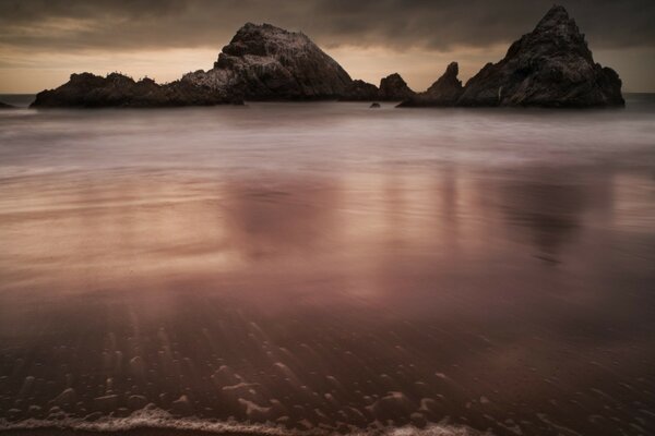 Boulders are reflected in the dark water