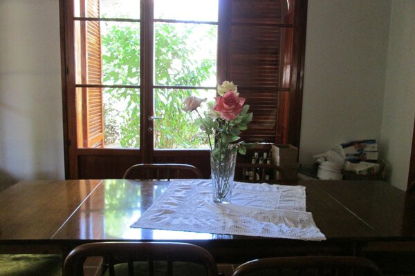 A vase with a rose on the table with a white tablecloth