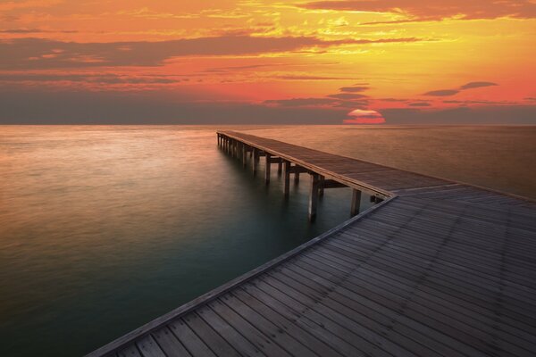 Blick auf den Sonnenuntergang vom Holzsteg am Meer