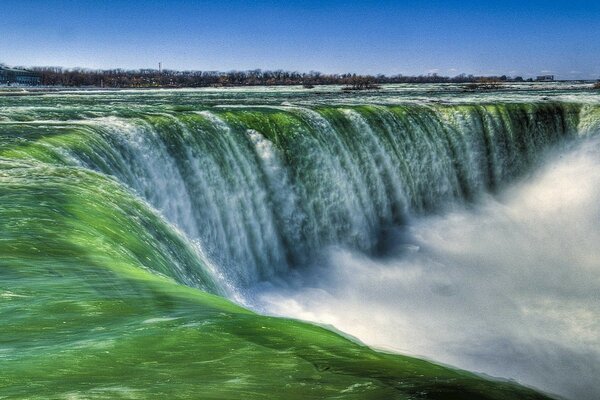 A river with a green shade and a waterfall