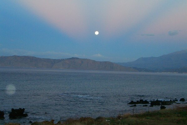 The distant sun over the lake and mountains