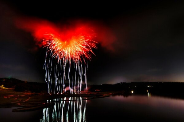 Hermosos fuegos artificiales sobre el agua por la noche