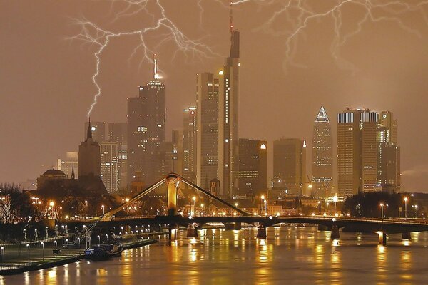 Lightning over high-rise buildings in the city near the bridge