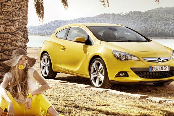 Тропикалық жағажайда сары және авто Opel Astra GT сары түсті қыз