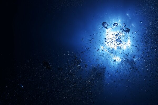 Underwater shooting of the Sun from under the blue water with bubbles