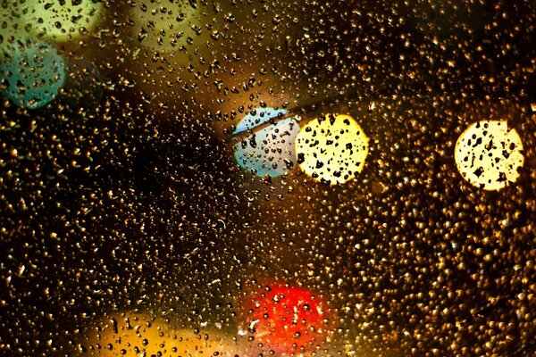 Drops on the glass and colorful lights outside the window