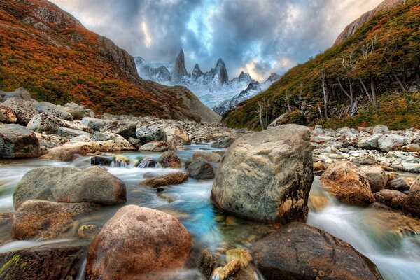 Um rio de montanha corre entre grandes pedras