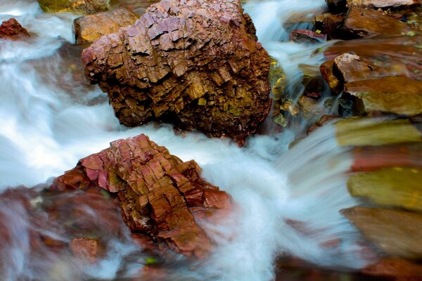 Brown stones among a waterfall on a blurry background