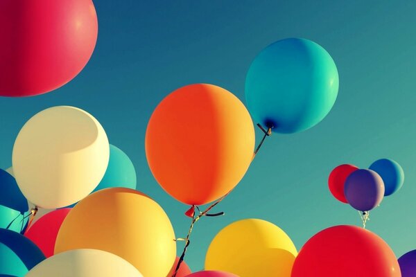 Multicolored helium balloons soar into the blue sky