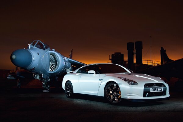 The car and the plane stand side by side on a dark background