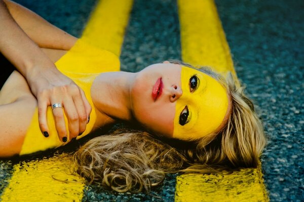 A woman poses lying on the asphalt