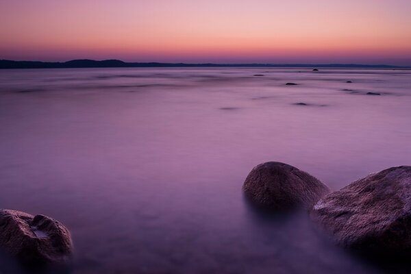 Puesta de sol en la playa con rocas y piedras