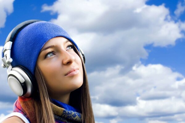 La chica del sombrero azul escucha música con auriculares