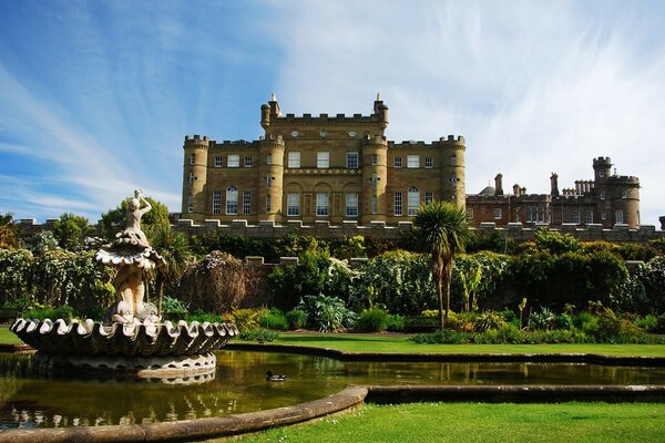 Castillo con una fuente y un estanque contra el cielo azul