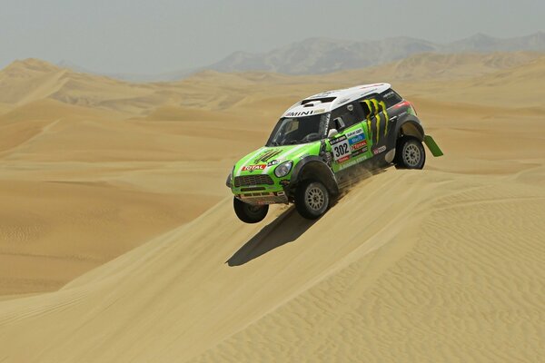 Une voiture de course surmonte un barkhan sablonneux