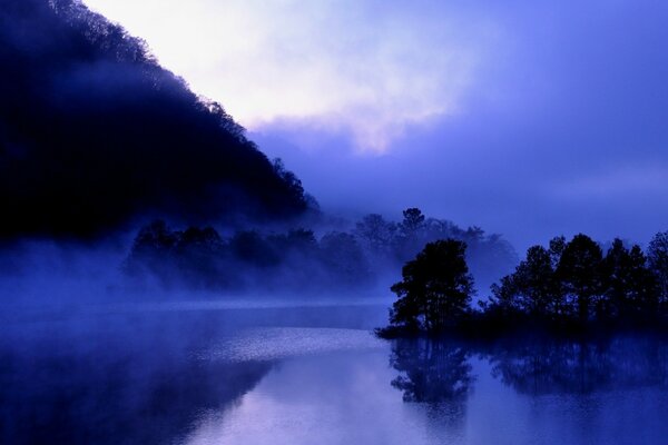 Niebla sobre un cuerpo de agua cerca de las montañas en tonos azules