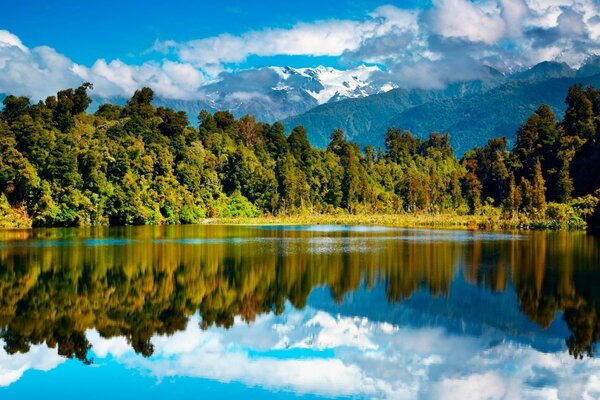 Forest, mountains and clouds are reflected in the lake