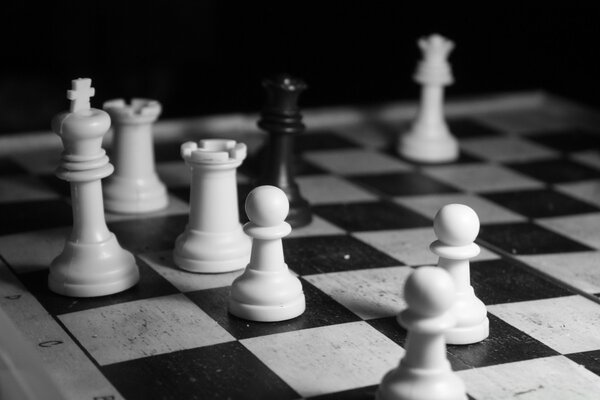 Un rey negro rodeado de piezas blancas en el ajedrez