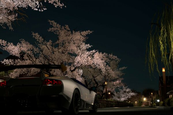 A gray car on an evening street lit by lanterns