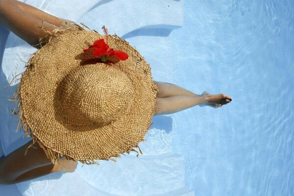 Chica con sombrero de vacaciones en la piscina