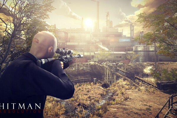 A hitman in a forest belt tracking through the optical sight of a gun