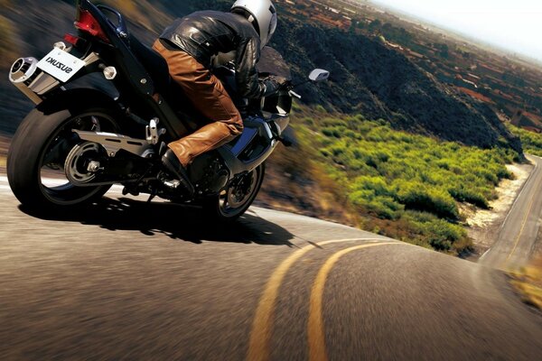 A biker rides a motorcycle down a steep mountainside