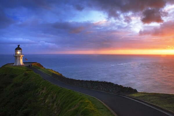 Estrada, mar e farol ao pôr do sol