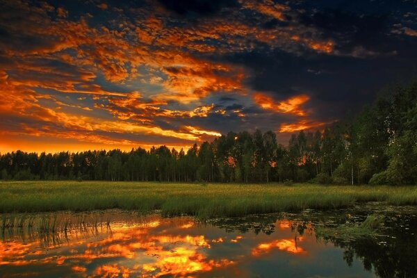 O pôr do sol de fogo é refletido na superfície da água do lago