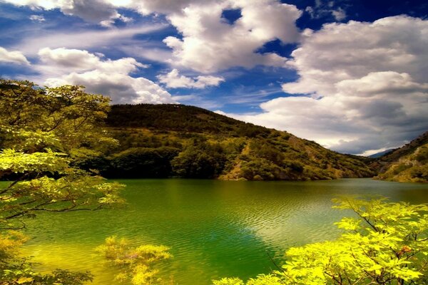 Lago tra le verdi colline. Cielo blu e nuvole bianche