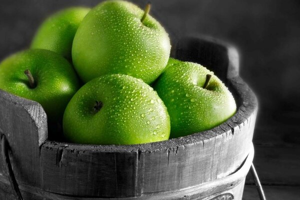 Manzanas verdes en una tina cubierta con gotas de agua