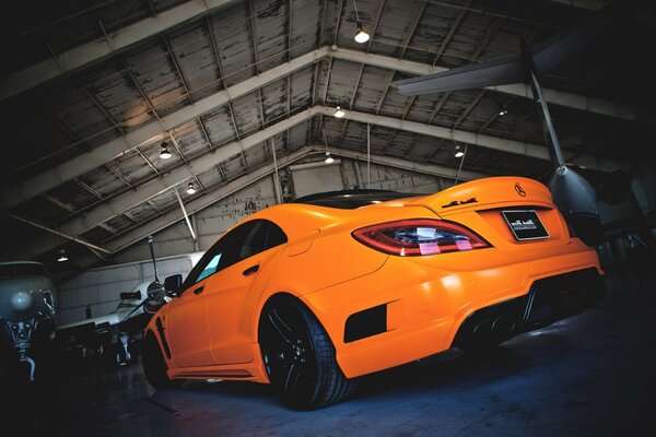 An orange Mercedes sports car in a hangar