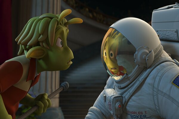 A teenage alien looks at his reflection in an astronaut s spacesuit